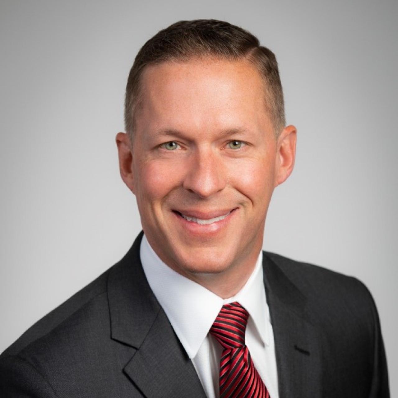 Head shot of Mike Triplett in suit with gray background