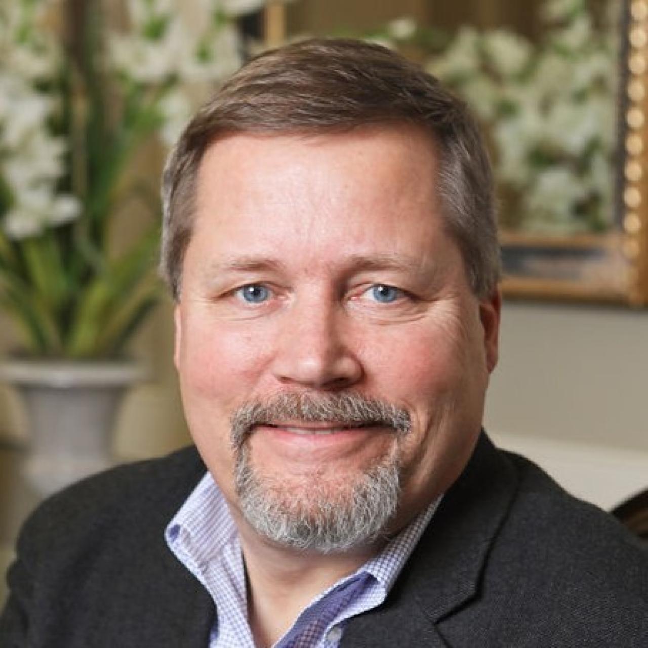 Image of Neil looking into camera with with zip up and collared shirt.