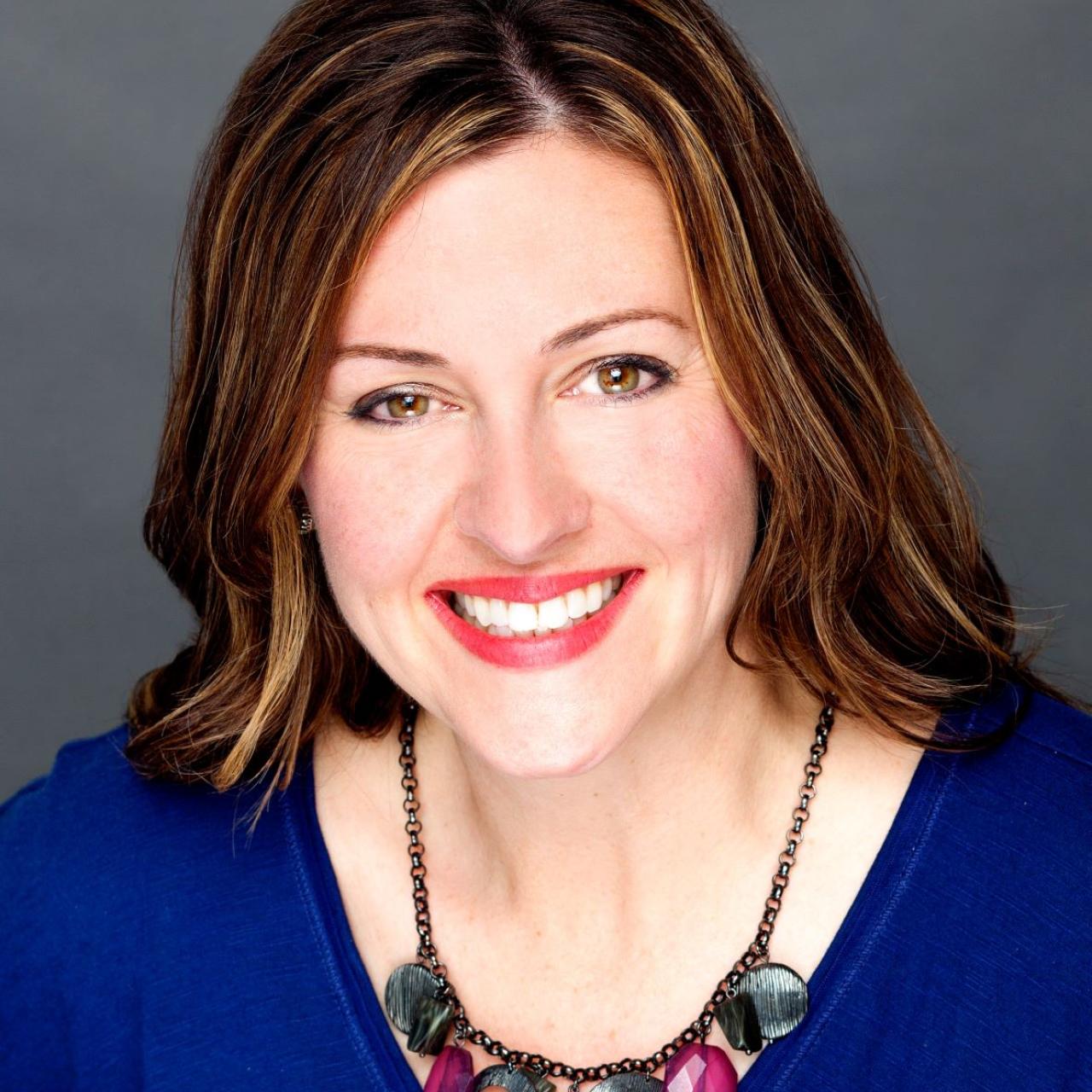 Image of Jennifer Scheehle smiling, wearing blue top and jeweled necklace