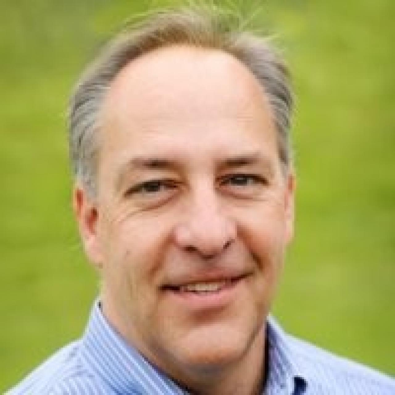 Image of Mark looking into camera wearing blue collared shirt.