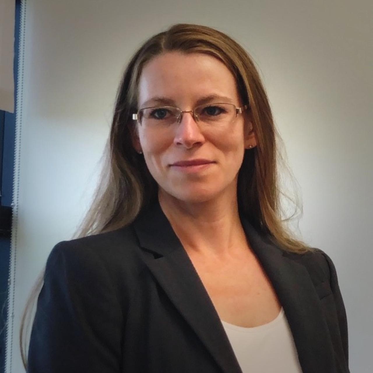 Image of Erica in suit coat, standing in office.