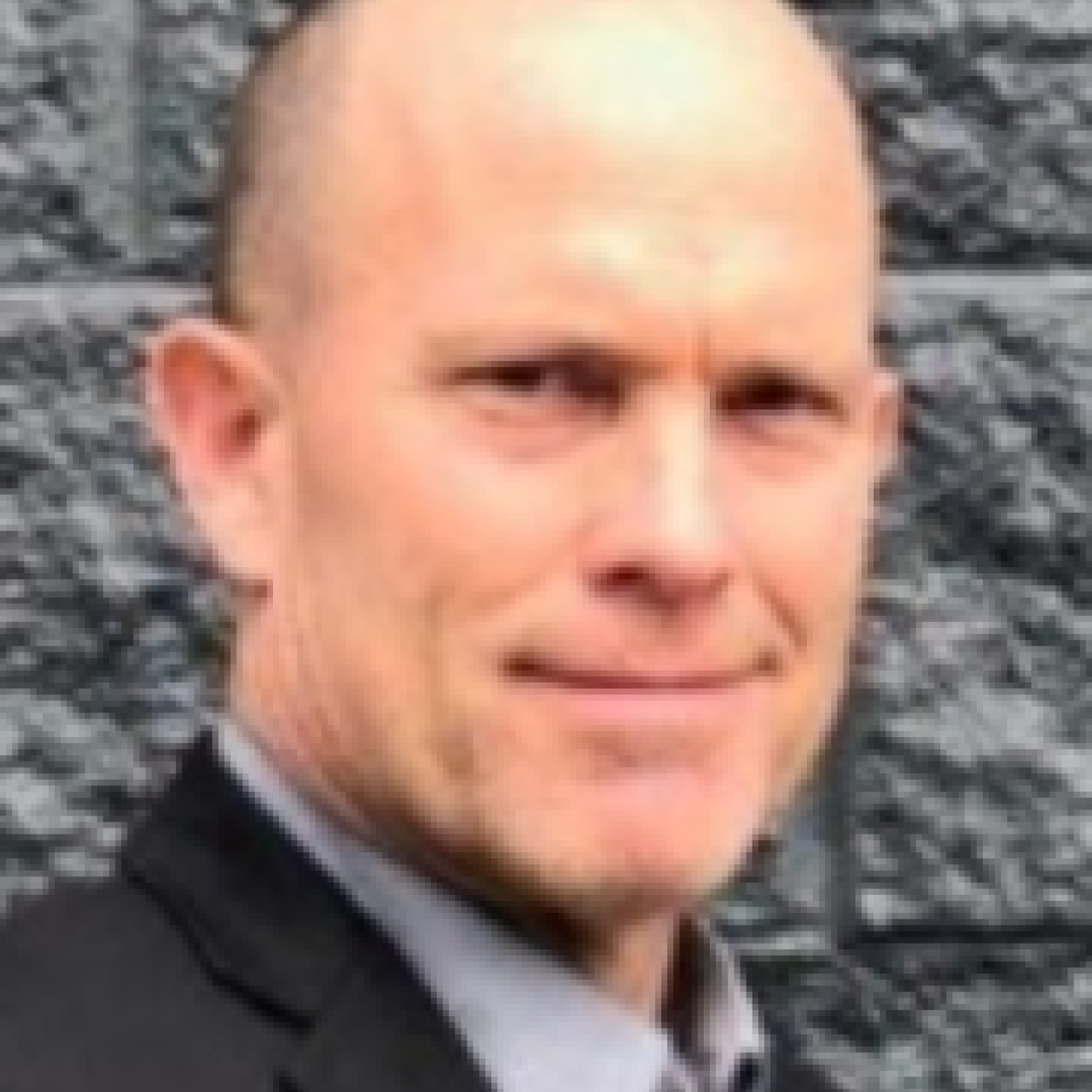 Image of Mark Zobel smiling, wearing a black suit coat and gray collared shirt