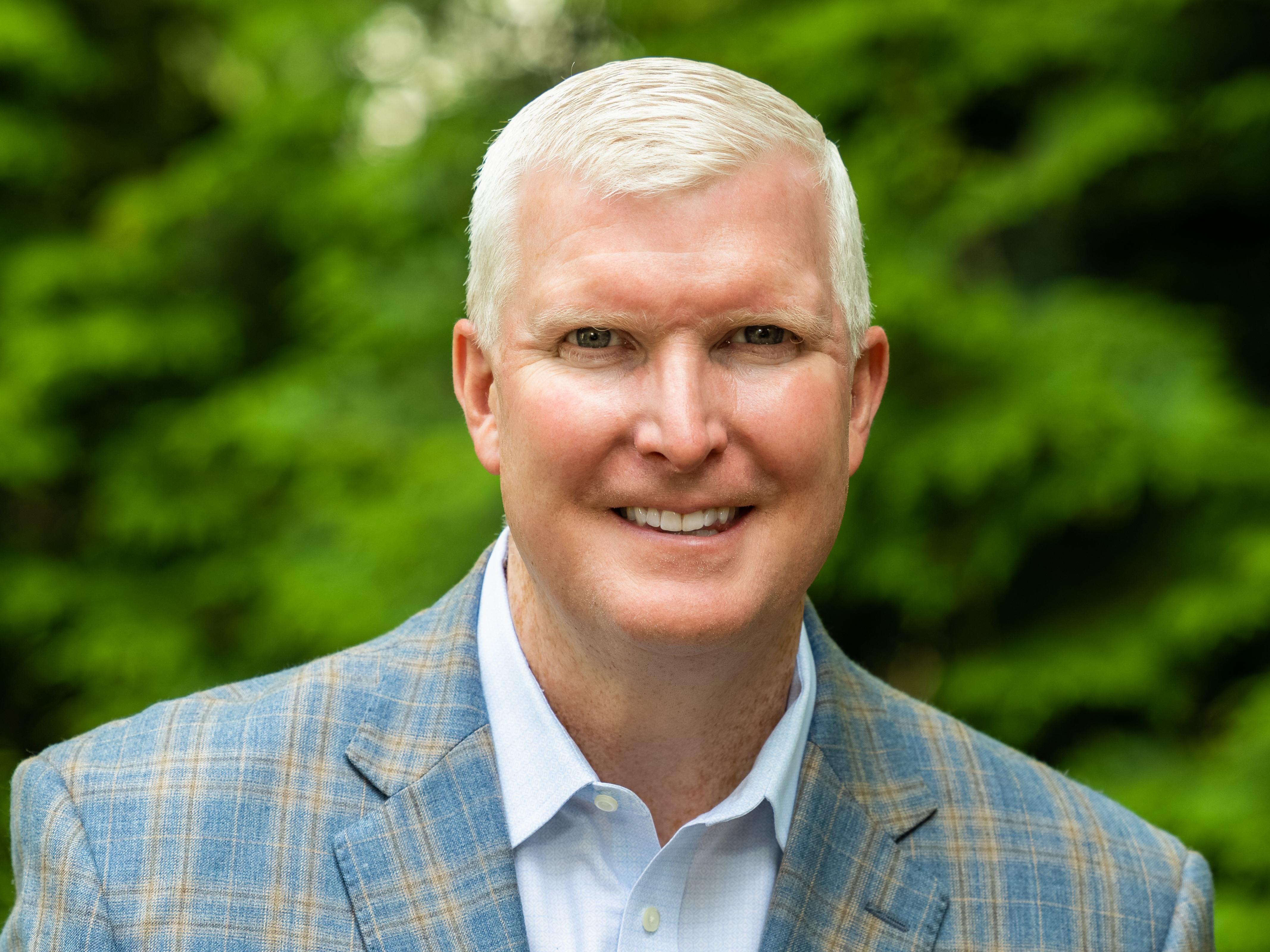 man in blue shirt and suit by trees