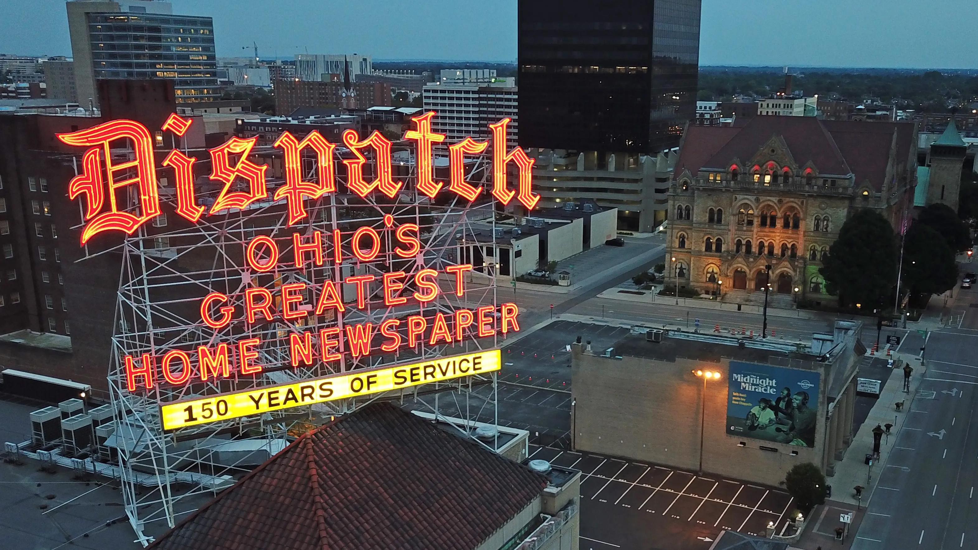 Columbus Dispatch lit up neon sign on top of building at night