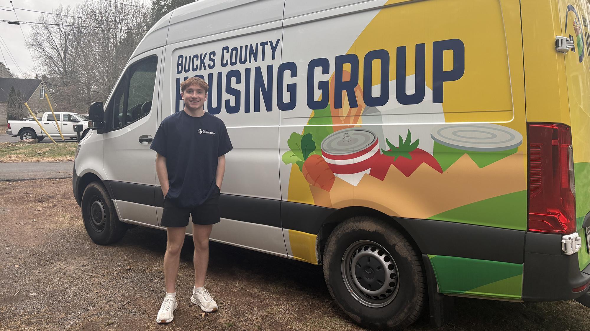 Young man stands beside a van.