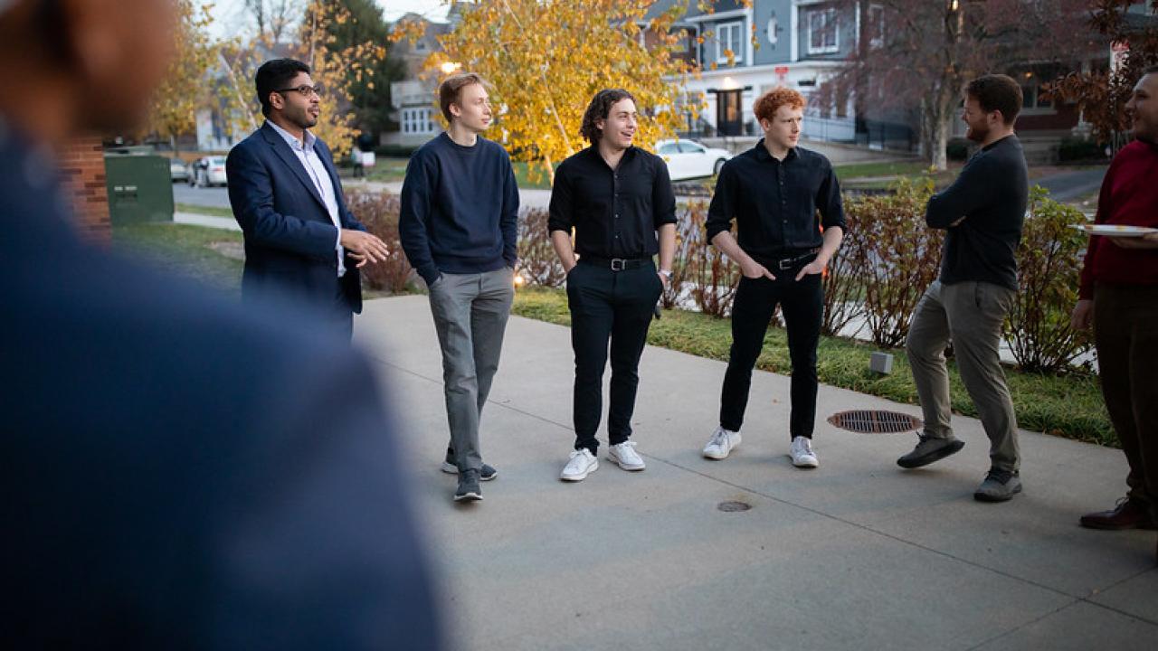 Five people sharing a conversation outdoors on a large sidewalk.